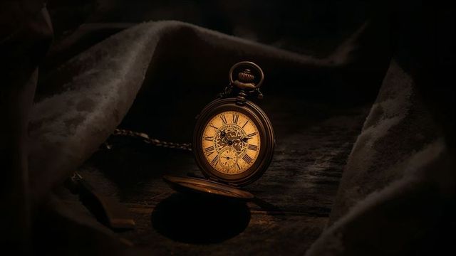 Vintage gold pocket watch on wooden surface in warm light