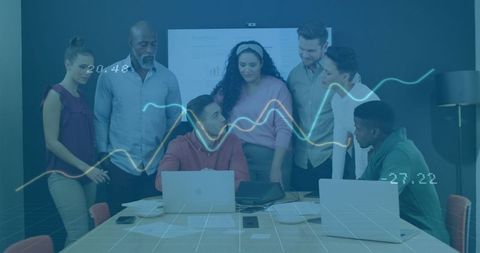 Diverse Team Analyzing Data With Technology in Modern Meeting