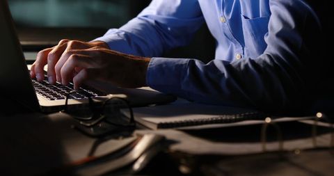 Businessman Typing at Night in Dimly Lit Office