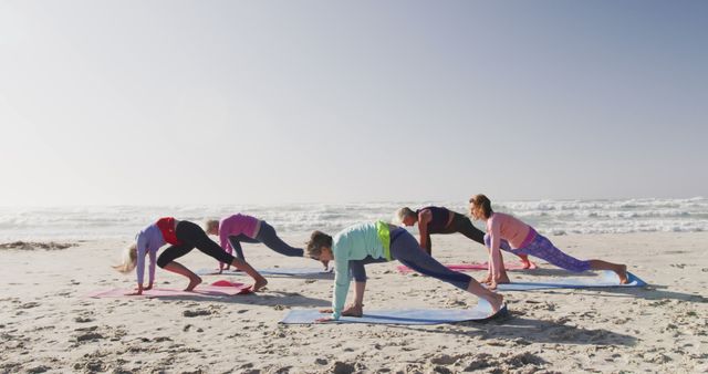 Diverse women wearing sports clothes doing yoga and stretching at beach. Sport, friendship, healthy and active lifestyle.