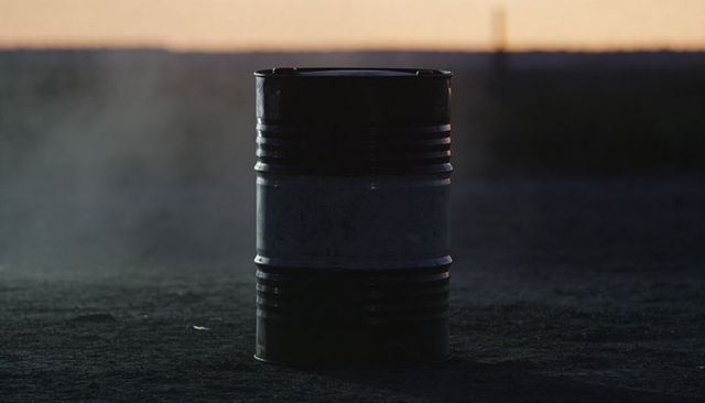 Solitary Rusted Metal Barrel Standing on Gritty Industrial Lot at Dusk with Mist