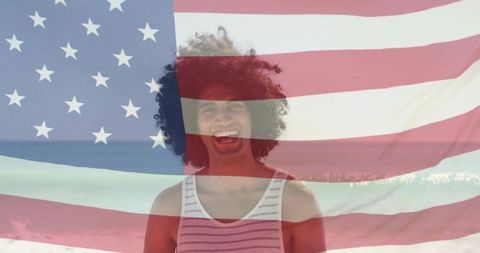 Smiling young man with curly hair on sunlit beach with translucent american flag overlay