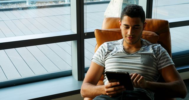 Young man relaxing indoors while using digital tablet - Download Free Stock Images Pikwizard.com