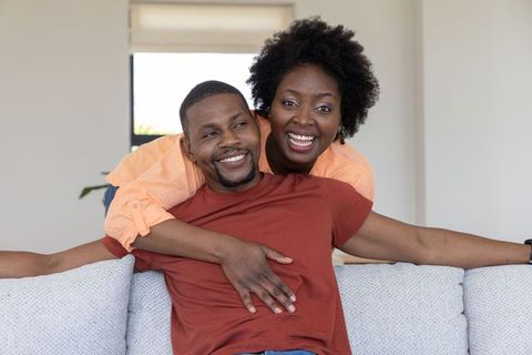 Smiling african american couple hugging on sofa in cozy modern living room