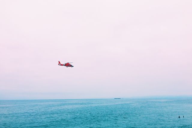 Red Helicopter Flying Over Ocean During Cloudy Day - Download Free Stock Photos Pikwizard.com