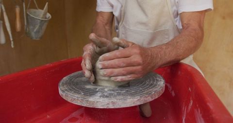Senior potter masterfully creating clay pot on wheel