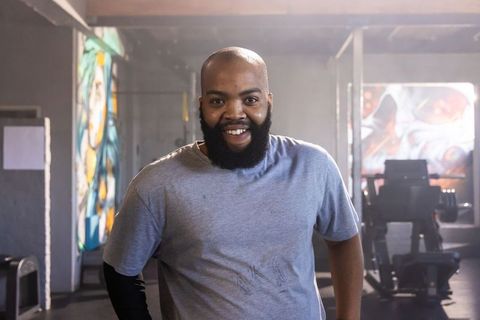 Bearded man smiling and posing after workout in urban gym with colorful mural