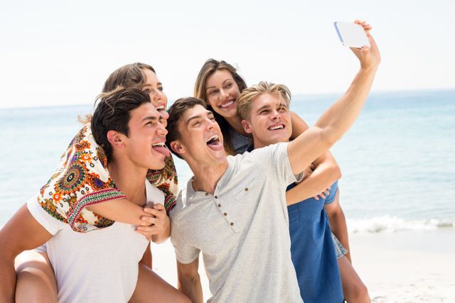 Group of friends enjoying a sunny day at the beach, taking a selfie together. Perfect for use in travel promotions, summer vacation advertisements, social media campaigns, and lifestyle blogs highlighting friendship and outdoor activities.