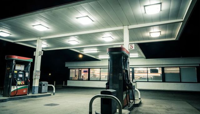 Deserted gas station canopy at night with illuminated fuel pumps and empty forecourt