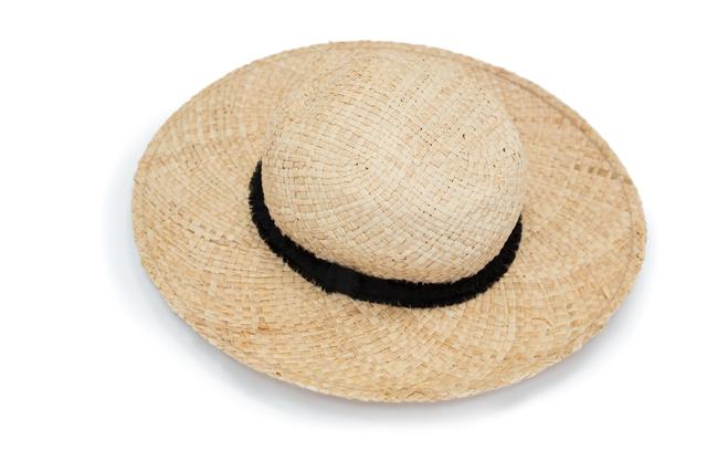 This image features a close-up of a straw hat with a black band, isolated on a white background. Ideal for use in summer fashion articles, beach vacation promotions, sun protection advertisements, and accessory catalogs. The neutral background makes it easy to integrate into various design projects.