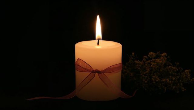 Burning Candle with Ribbon and Flowers Creating Ambient Serenity