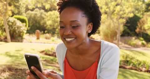 Joyful Woman Laughing While Using Smartphone in Park