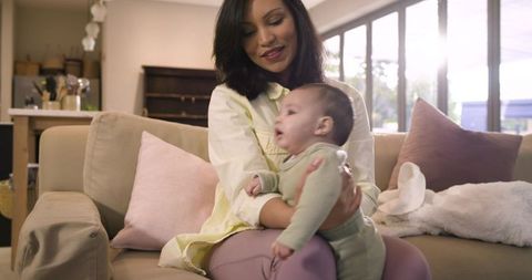Mother Nurturing Infant in Cozy Sunlit Living Room