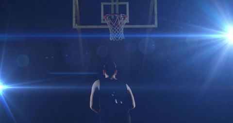 Basketball player standing under hoop with flare lights