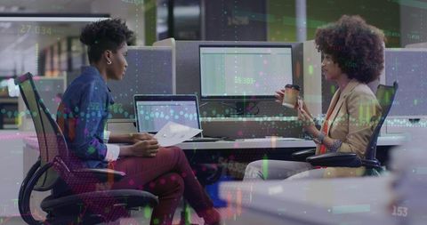 Businesswomen analyzing data on computer screens in modern office