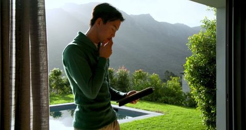 Man Contemplating in Modern Home with Tablet by Poolside