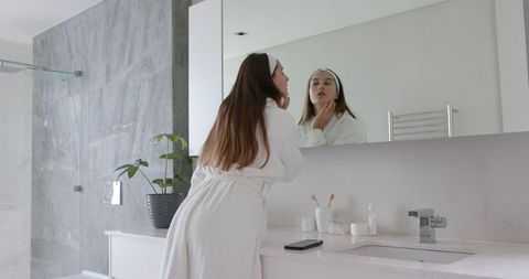 Woman practicing skincare routine in minimalistic bathroom