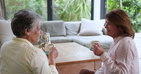 Senior Mother and Daughter Relaxing with Coffee in Cozy Living Room