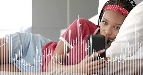 Young woman reclining on bed using smartphone with waveform overlay for digital wellbeing