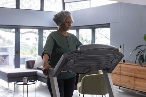 Senior woman using treadmill in modern living room for fitness