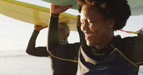 Joyful surfers carrying boards on sunny beach adventure