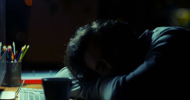 Man Sleeping on Desk in Dimly Lit Room at Night - Download Free Stock Images Pikwizard.com