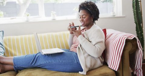 Relaxed Woman Using Smartphone and Laptop at Home