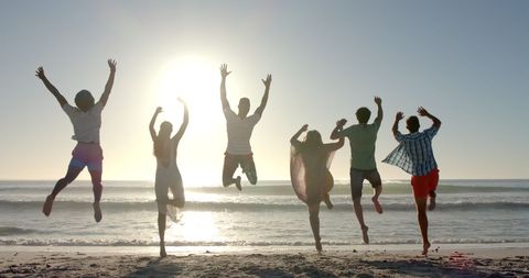 Group of Friends Joyfully Jumping at Sunset Beach