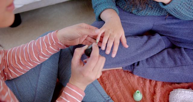 Close-up shot shows woman carefully applying nail polish to another woman's hand, highlighting personal grooming and relaxation. Ideal for promoting self-care routines, DIY beauty, at-home spa experiences, or products related to nail care and personal wellness.