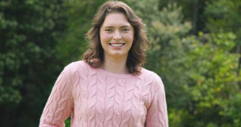 Smiling Woman in Pink Sweater Outdoors in Lush Garden