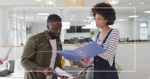 Team Collaborating Over Blue Folder and Clipboard in Modern Office Lounge