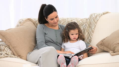 Mother and Daughter Sharing Quality Time with Photo Album on Sofa