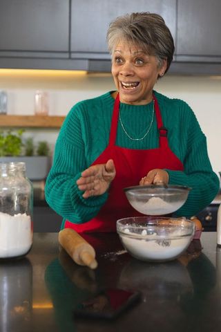 Senior woman joyfully baking with flour in cozy kitchen
