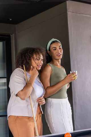 African american friends playing pool in modern rec room socializing by billiards table