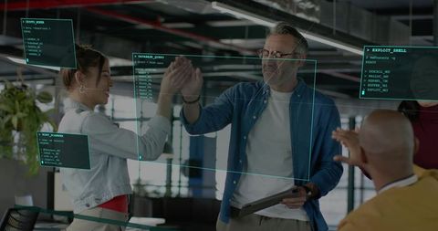 High-fiving tech team celebrating cybersecurity win with tablet and teal holographic ui