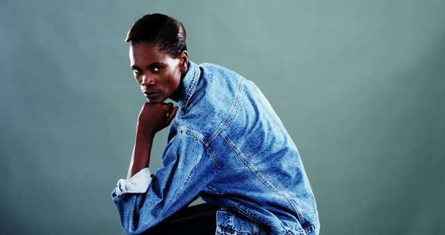 An African American woman poses confidently in a denim jacket, with copy space. Her strong gaze and dynamic posture convey a sense of empowerment and style.