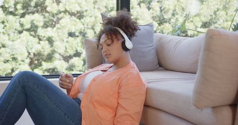 Relaxed African American Woman Wearing Headphones at Home by Window