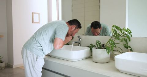 Man Washing Face in Modern Minimalist Bathroom with Stylish Sink