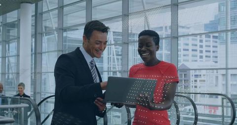 Business colleagues collaborating on laptop in contemporary office lobby