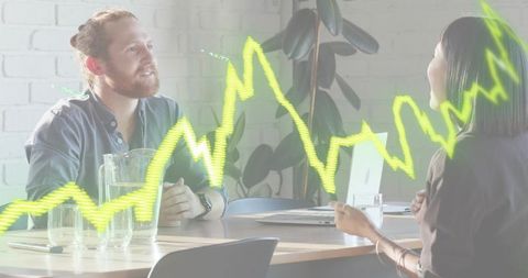 Modern colleagues discussing data analytics over laptop with neon chart overlay in office