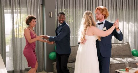 Mixed-ethnicity couples dancing joyfully at wedding reception