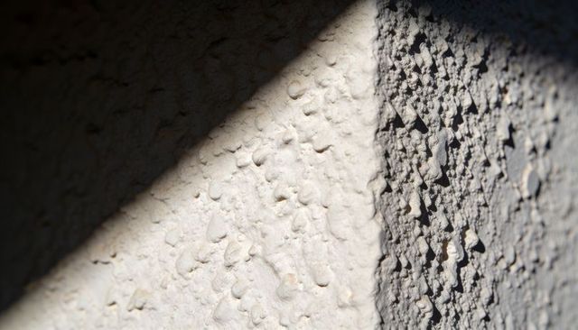 Sunbeam Carving Stucco Corner Revealing Rough Plaster Texture and Shadow Contrast