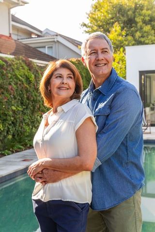 Senior Couple Embracing by Backyard Pool Smiling Peacefully