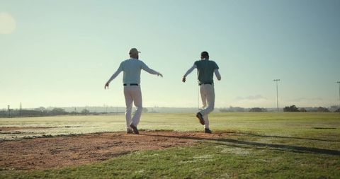 Diverse male baseball teammates walking across infield at golden hour showing teamwork
