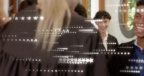 Graduates adjusting academic gowns in dressing room with mirrored reflections and stars