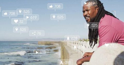 Man in Pink Polo Standing by Ocean with Social Media Interaction Icons