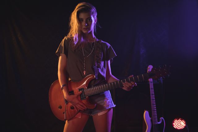 Portrait of female musician playing guitar in nightclub