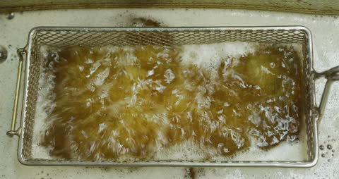 Overhead View of Potatoes in Deep Fryer with Bubbling Oil in Kitchen