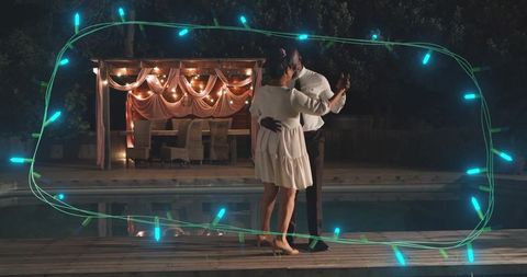 Couple dancing on pool deck at night with gazebo lights, reflections and teal light overlay