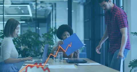 Collaborative team reviewing reports with rising sales graph in modern office meeting